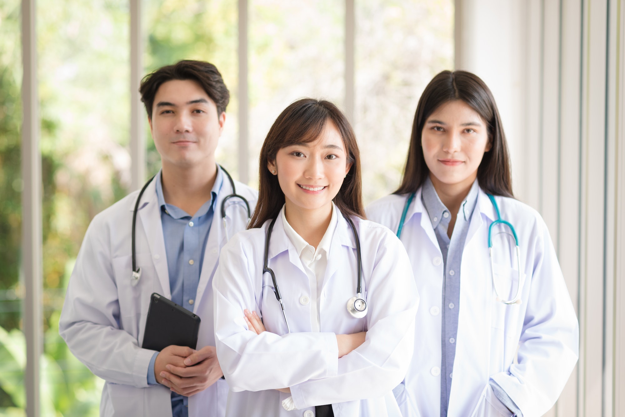 Group of Asian doctors team portrait standing with colleagues in background.